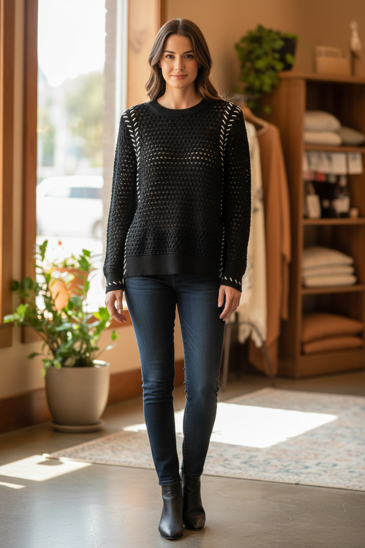 Woman wearing a black Tribal open-knit sweater with white arrow-like accents along the raglan seams and cuffs in a front-facing pose.