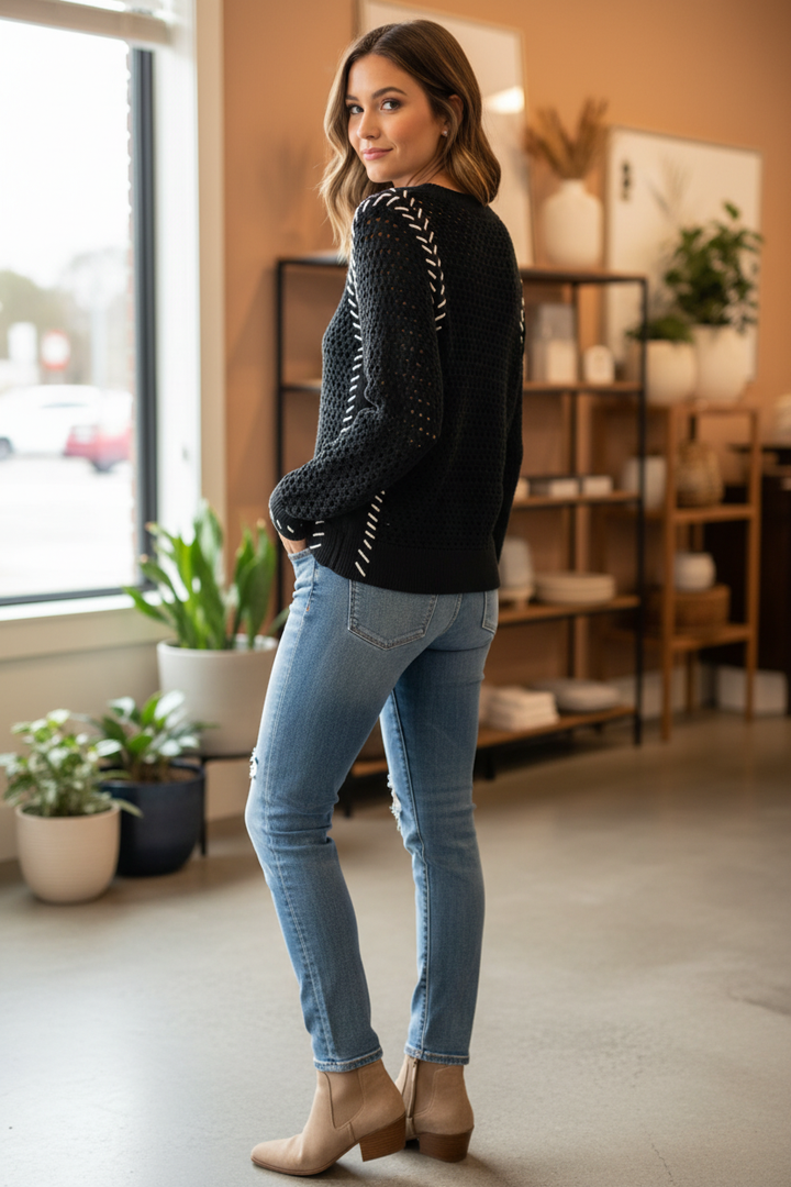 Woman wearing a black Tribal open-knit sweater with white arrow-like accents along the raglan seams and cuffs in a three-quarter pose.